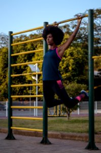 Woman Hanging On Climb Bar On Park