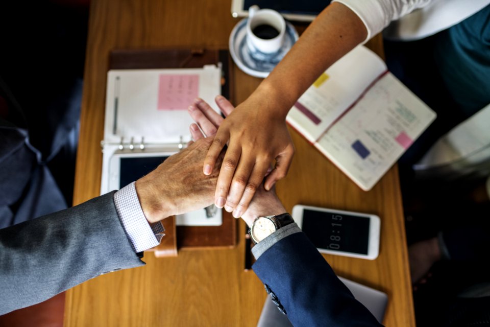 Three Persons Hands On Center Near Table