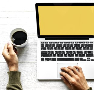 Persons Hand On Laptop And Holding Coffee photo