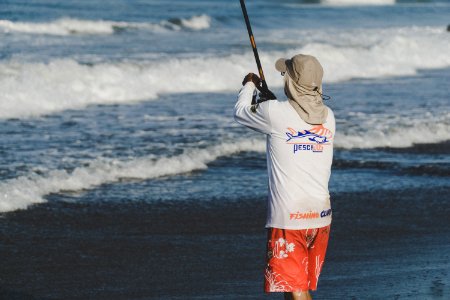 Person Holding Fishing Rod On Beach