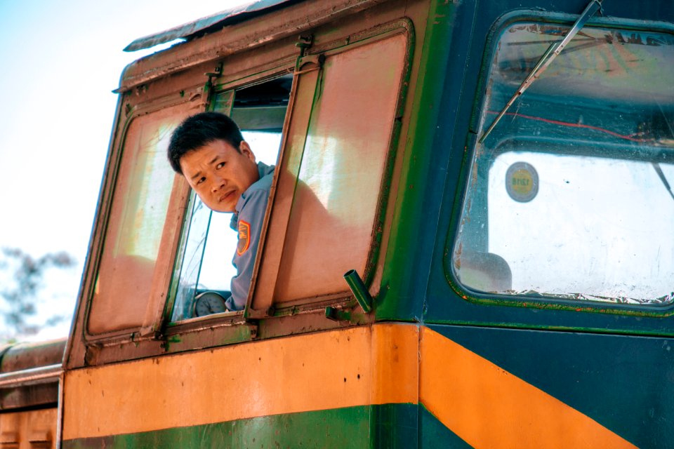 Man Wearing Blue Shirt Driving Green And Yellow Vehicle