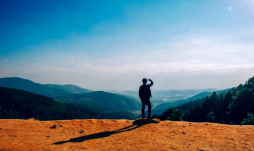 Silhouette Of Man Standing On Mountain Cliff photo