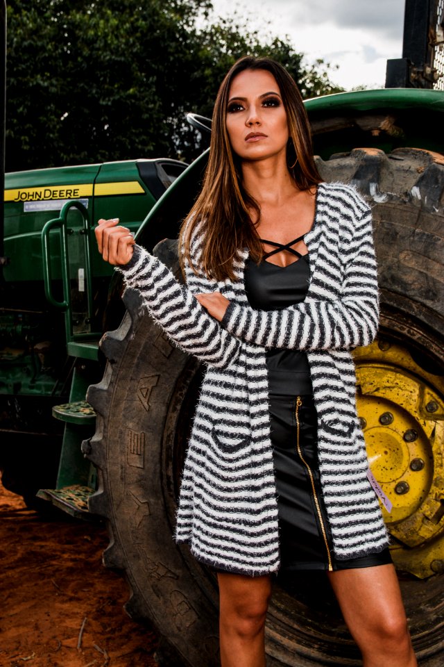 Woman Wearing Pink And Black Striped Long Cardigan Standing Behind John Deere Tractor At Daytim E