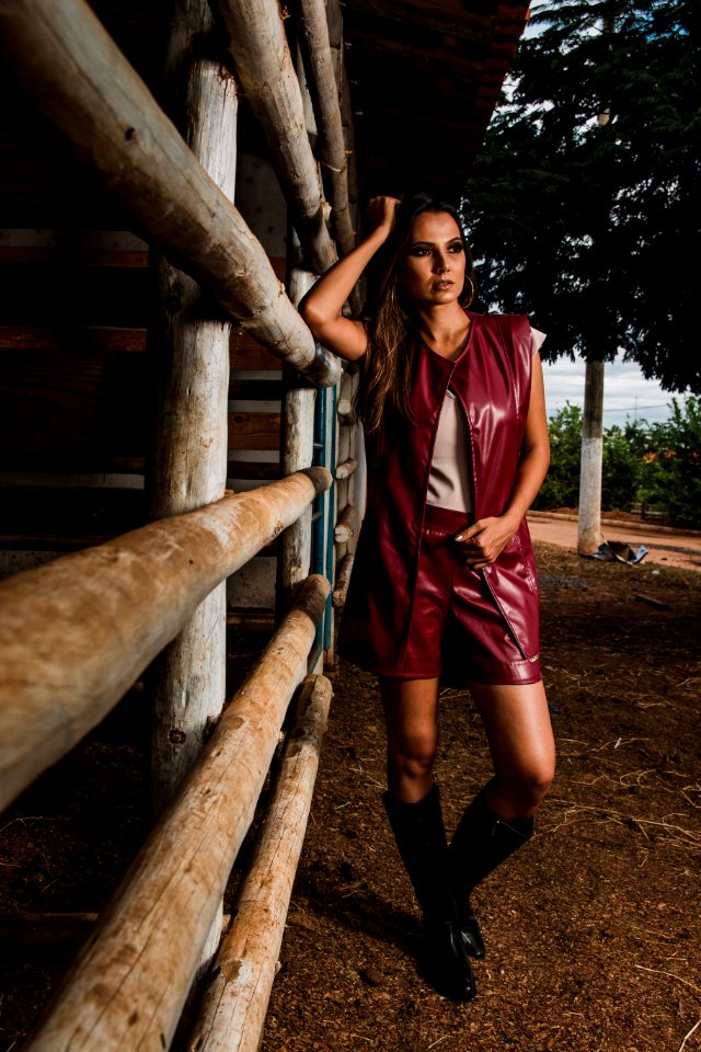Woman Wearing Maroon Leather Sleeveless Jacket Beside Horse Stable