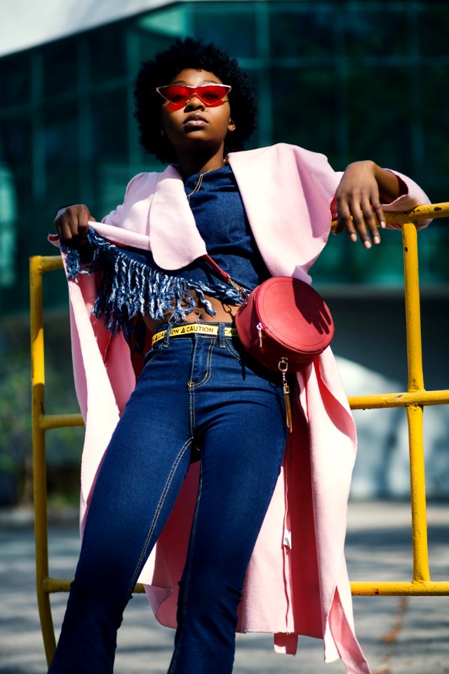Woman Wearing Jeans Leaning On Yellow Metal Bar