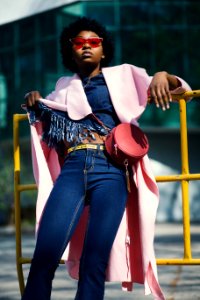 Woman Wearing Jeans Leaning On Yellow Metal Bar photo