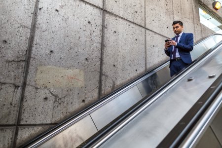 Man Wearing Blue Suit Holding Smartphone On Escalator photo