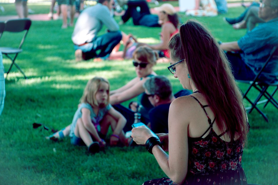 Man Wearing Black And Red Floral Spaghetti-strap Shirt Using Smartphone Sitting On Green Grass At Daytime