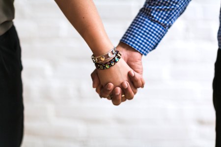 Couple Holding Hands Near White Painted Wall photo