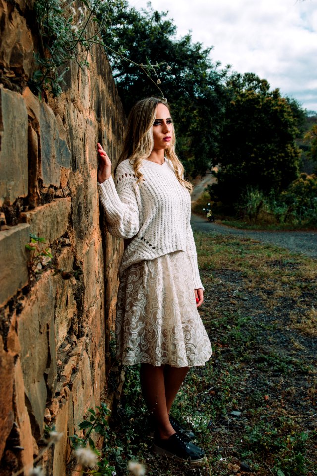 Photo Of Woman In White Long-sleeved Shirt Beside Concrete Wall