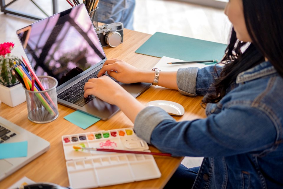 Woman Using Black Laptop While Leaning On Brown Wooden Table photo