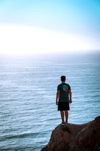 Man Standing On Cliff Near Sea photo