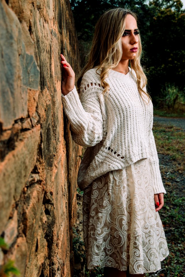 Woman In Knitted V-neck Long-sleeved Shirt And Midi Skirt Standing Beside Wall
