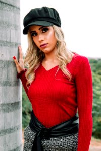 Woman Wearing Black Cap And Red V-neck Sweatshirt Near Concrete Wall photo