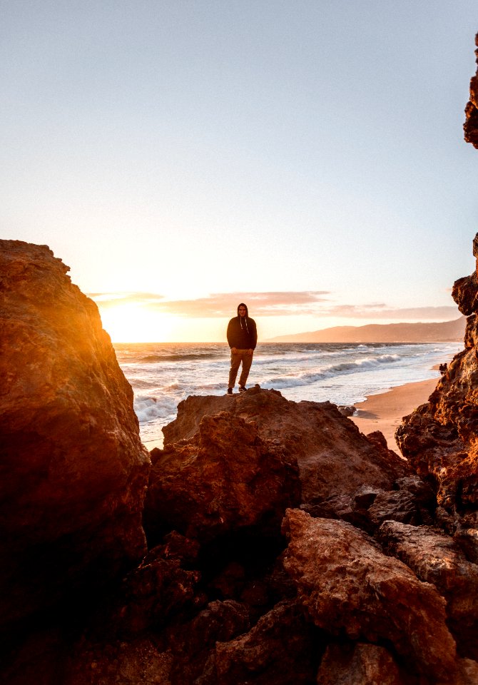 Photography Of A Man Standing On A Rock