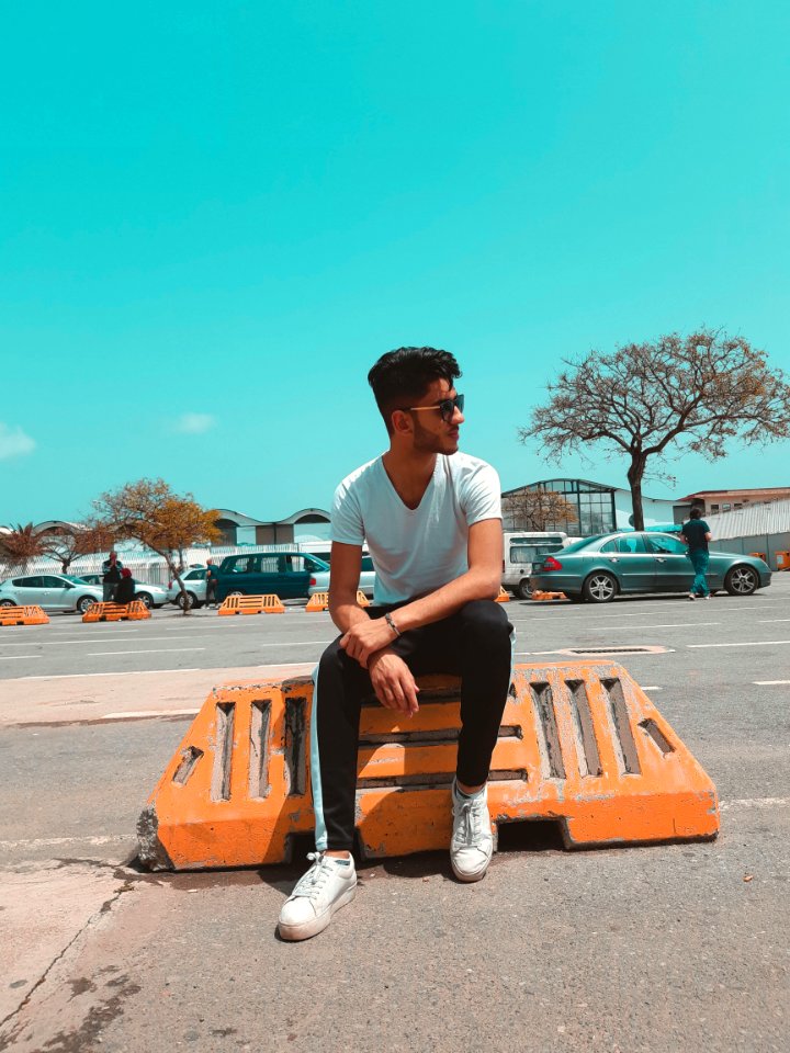 Man In White Shirt Sitting On Orange Concrete photo