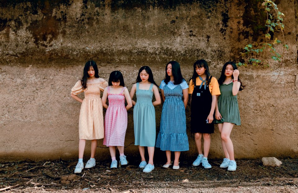 Six Women Leaning On Brown Wall photo