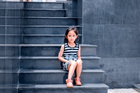 Girl Wearing Black And White Striped Dress Sitting On Stair photo
