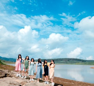 Group Of Women Wearing Dress Standing Near Body Of Water photo