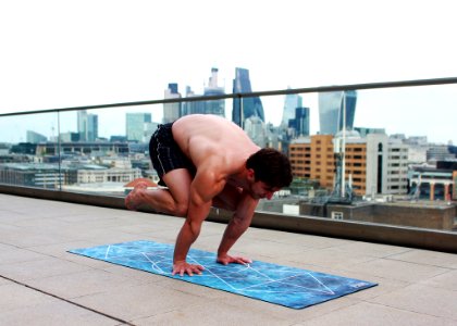 Man Doing Yoga On Mat Near Glass Balcony Fence photo