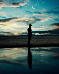 Silhouette Of Man Standing Near Body Of Water photo