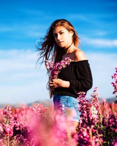 Woman In Black Long-sleeved Off-shoulder Top And Blue Denim Short Shorts Holding Flowers photo