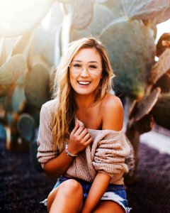Woman In Brown Sweater And Distressed Blue Denim Shorts Beside Green Cactus photo
