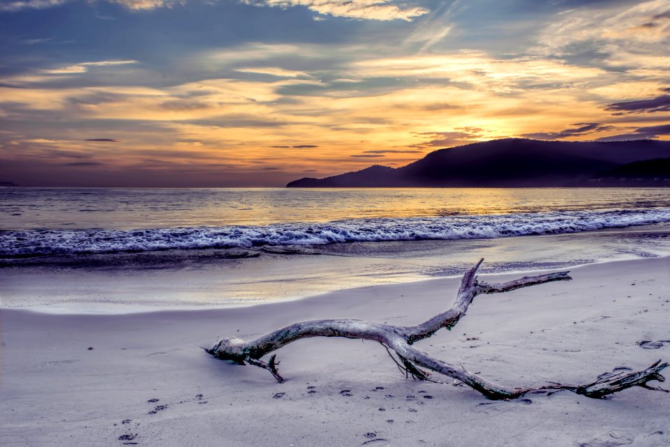 Body Of Water Near Mountain Under Gray Sky At Golden Hour