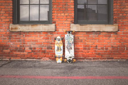 Two White And Brown Longboard Leaning On Brown Bricks Wall photo
