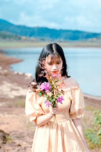Woman In Orange And White Gingham Check Off-shoulder Dress Holding Pink Petaled Flowers