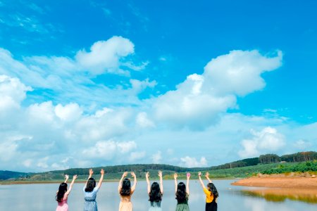 Group Of Women Wearing Dress Raising Up Their Hands On Air Under Cloudy Sky photo