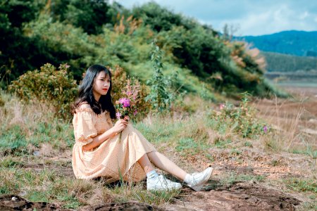 Woman With Beige Dress And White Shoes Sitting On Green Grass
