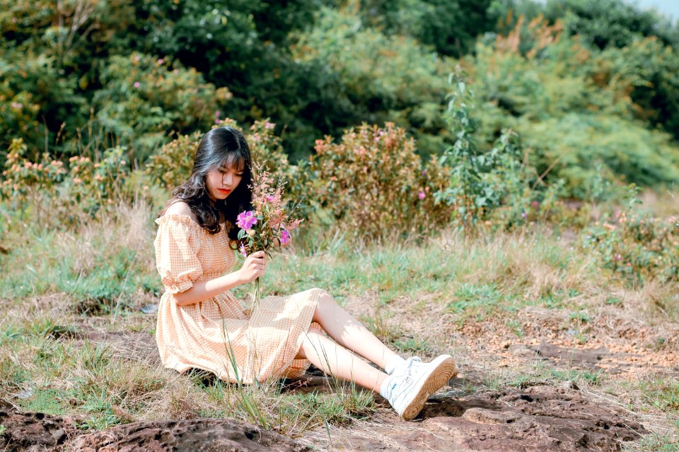 Woman Sitting On Ground And Holding Flower