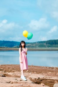 Woman Holding Balloons Standing On Beige Sand photo