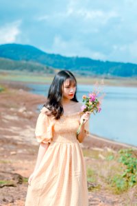 Shallow Focus Photography Of Woman In Beige Off-shoulder Dress Holding Bouquet Of Flowers photo