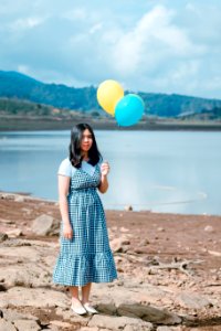 Woman In White And Black Dress Stands While Holding Party Balloons photo