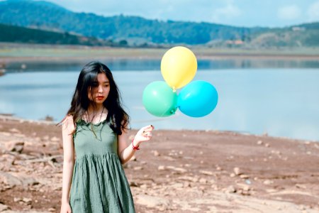 Woman In Green Sleeveless Dress Holding Three Balloons photo