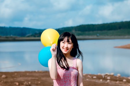 Woman In Pink Thick Strap Top Holding A Yellow And Blue Balloons photo