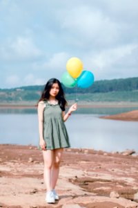 Womans In Green Sleeveless Dress Holding 3 Balloons photo