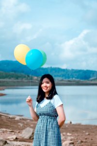 Shallow Focus Photography Of Woman In White And Black Short-sleeved Dress Holding Balloons photo