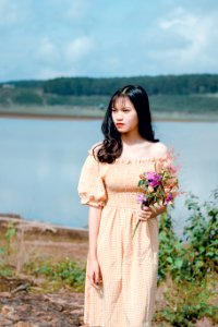 Shallow Focus Photography Of Woman In Yellow Off-shoulder Dress Holding Flower Bouquet photo