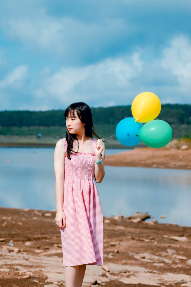 Woman Wearing Pink Dress Holding Three Balloons Near Body Of Water