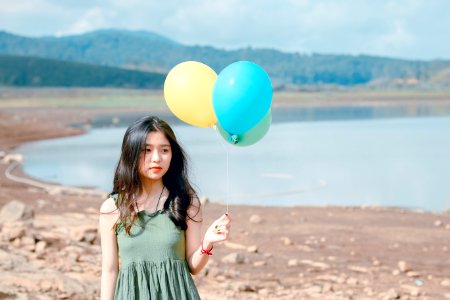 Shallow Focus Photography Of Woman Holding Three Assorted-color Balloons photo