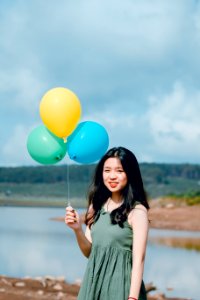 Woman Wearing Green Dress Holding Balloons Near River photo