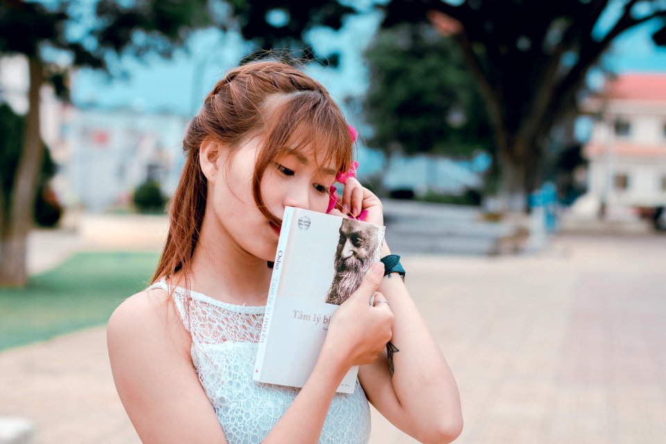 Woman Wearing White Lace Top Holding Book