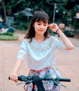 Woman Wearing White Blouse And Multicolored Floral Skirt Riding Bike photo