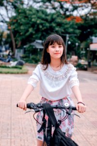 Woman Wearing White Blouse And Multicolored Floral Skirt Riding Bike photo