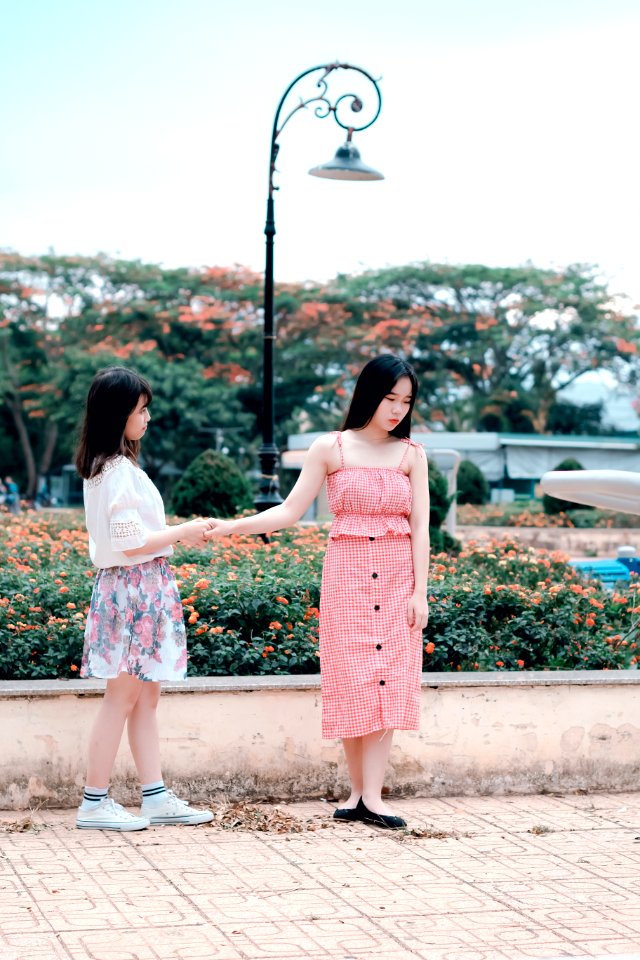 Two Women Holding Hands Under Green Metal Post Lamp
