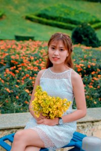 Focus Photo Of Woman Wearing Dress While Holding Bouquet Of Yellow Flowers photo