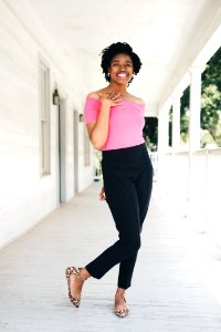 Woman Wearing Pink Off-shoulder Shirt And Black Pants While Standing Near Wall photo